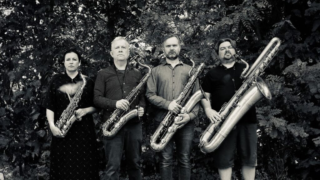 Neljä henkilöä seisovat rivissä saksofonit kädessään.