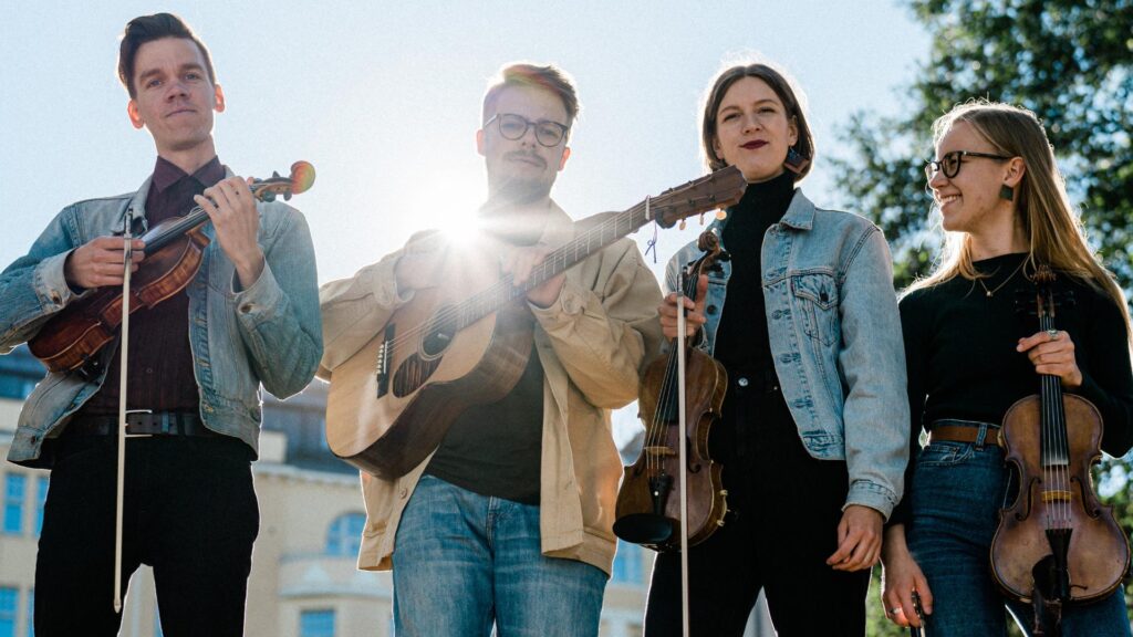 Neljä henkilöä taivasta vasten soittimet kädessä