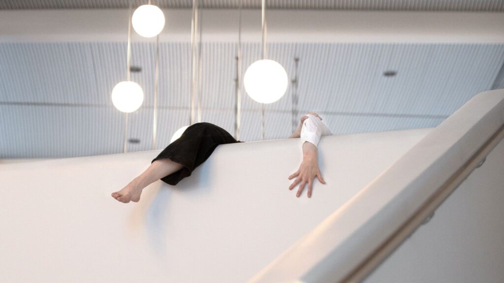 Henkilö roikkuu kaiteessa, vain käsi ja jalka näkyvät