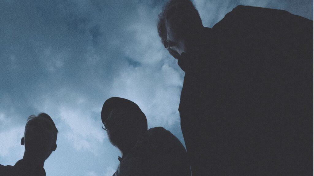 Kolme hahmoa taivasta vasten.